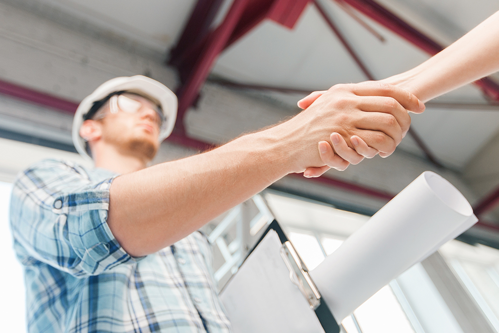 Two workers on the roof of a building working on the air conditioning unit.